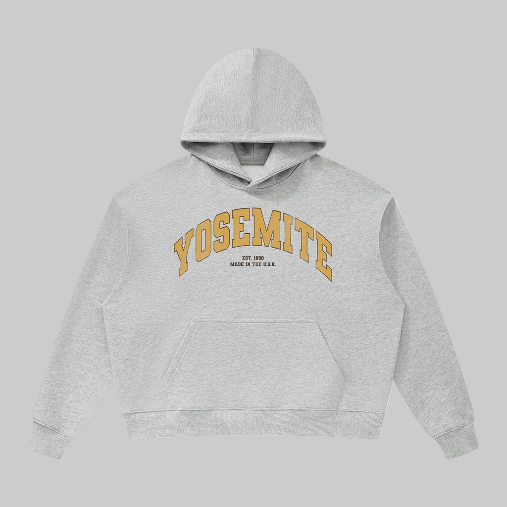 A light heather gray pullover hoodie with 'YOSEMITE' printed in an arched gold font across the chest, with smaller text underneath reading 'EST. 2009' and 'MADE IN THE U.